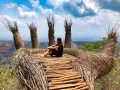 Mujer sentada en una mano gigante de ramas, disfrutando de la vista. Un lugar perfecto para viajar a Java, Indonesia.