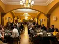 Gente disfrutando de una cena en un elegante restaurante con arcos y lámparas doradas. Una experiencia culinaria memorable para comer en Olite.