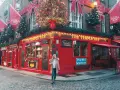 Una mujer pasea por la calle empedrada frente al icónico pub The Temple Bar en Dublín, decorado para Navidad. ¡Una excelente idea de qué hacer en Dublín!