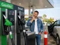 Hombre pensativo frente a surtidores de gasolina y diésel. ¿Cuál elegir para su viaje?