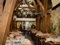 Mesas puestas en un restaurante rústico con vigas de madera y paredes de piedra, ideal para comer en Avilés.