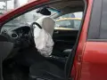 Interior de coche rojo con airbag del conductor desplegado, indicando la dirección del vehículo activa o pasiva tras un impacto.