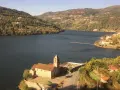 Un pueblo pintoresco a orillas de un río, con una iglesia y un cementerio. Las colinas verdes y las casas se extienden hasta donde alcanza la vista. ¡Un lugar ideal para ir a toro!