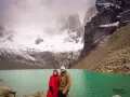 Pareja posa frente a un lago turquesa y montañas nevadas, un paisaje imperdible que ver en Chile.