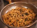 Pasta con salsa cremosa y hierbas en sartén. ¡Una deliciosa opción para saber dónde comer en Madrid!
