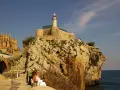 Descubre qué ver en Castro Urdiales: un faro en un castillo sobre rocas, con una iglesia gótica al fondo y gente paseando.