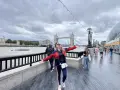 Mujer sonriente con brazos extendidos en Londres, con la Torre de Londres y el Tower Bridge al fondo. ¡Excelentes consejos para viajar a Londres!