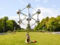 Familia posa frente al Atomium, un icono de que ver en Bruselas. Un niño salta detrás de su madre en el césped.