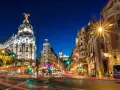 Noche vibrante en Madrid, con edificios iluminados y estelas de luz de coches. ¡Un fin de semana en Madrid inolvidable!
