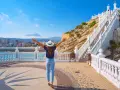 Mujer con brazos abiertos admira la vista de Benidorm desde el mirador. ¡Un lugar ideal que ver en Benidorm!