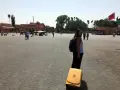 Una mujer con mochila y maleta amarilla en una plaza de Marruecos. Piensa en qué llevar a Marruecos para este viaje.