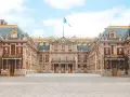 Palacio de Versalles, una visita obligada si buscas qué ver en París en 2 días. Majestuosa arquitectura y bandera francesa ondeando.