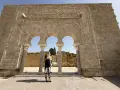 Mujer posa ante arcos de Medina Azahara. Se puede visitar Medina Azahara por libre, explorando su rica historia y arquitectura.