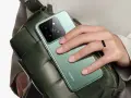 Mano con anillo sostiene un teléfono verde con cámara Leica, ideal para tus aplicaciones para viajar y capturar recuerdos.