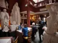 Un camarero sirve copas de vino en un restaurante único, rodeado de esculturas. Un lugar ideal donde comer en Roma.