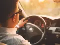 Hombre con gafas de sol conduce al atardecer. ¡Cuidado con la velocidad, te pueden multar!