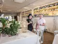 Pareja sonriente en un restaurante con estanterías llenas de vino. Un lugar ideal para saber donde comer en Logroño.