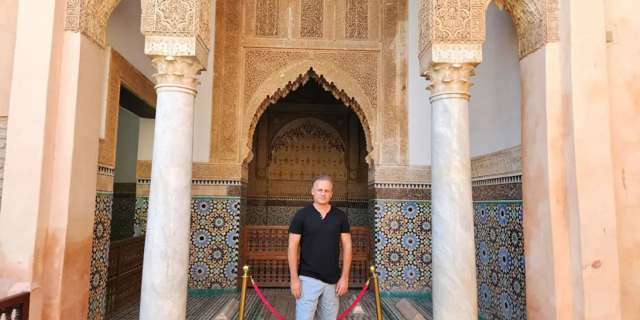 Hombre posa ante intrincada arquitectura marroquí. ¡Ideas para que ver en Marrakech en 2 días!
