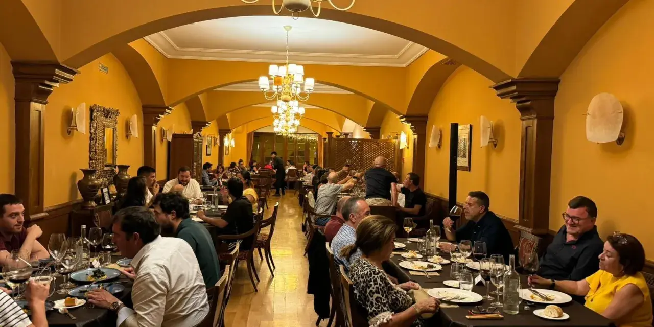 Gente disfrutando de una cena en un elegante restaurante con arcos y lámparas doradas. Una experiencia culinaria memorable para comer en Olite.