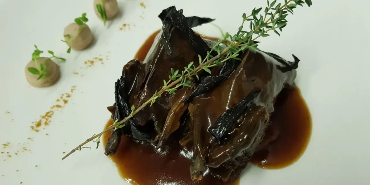 Plato de caza en salsa oscura, decorado con tomillo y puré de patatas. ¡Una opción deliciosa donde comer en Úbeda!