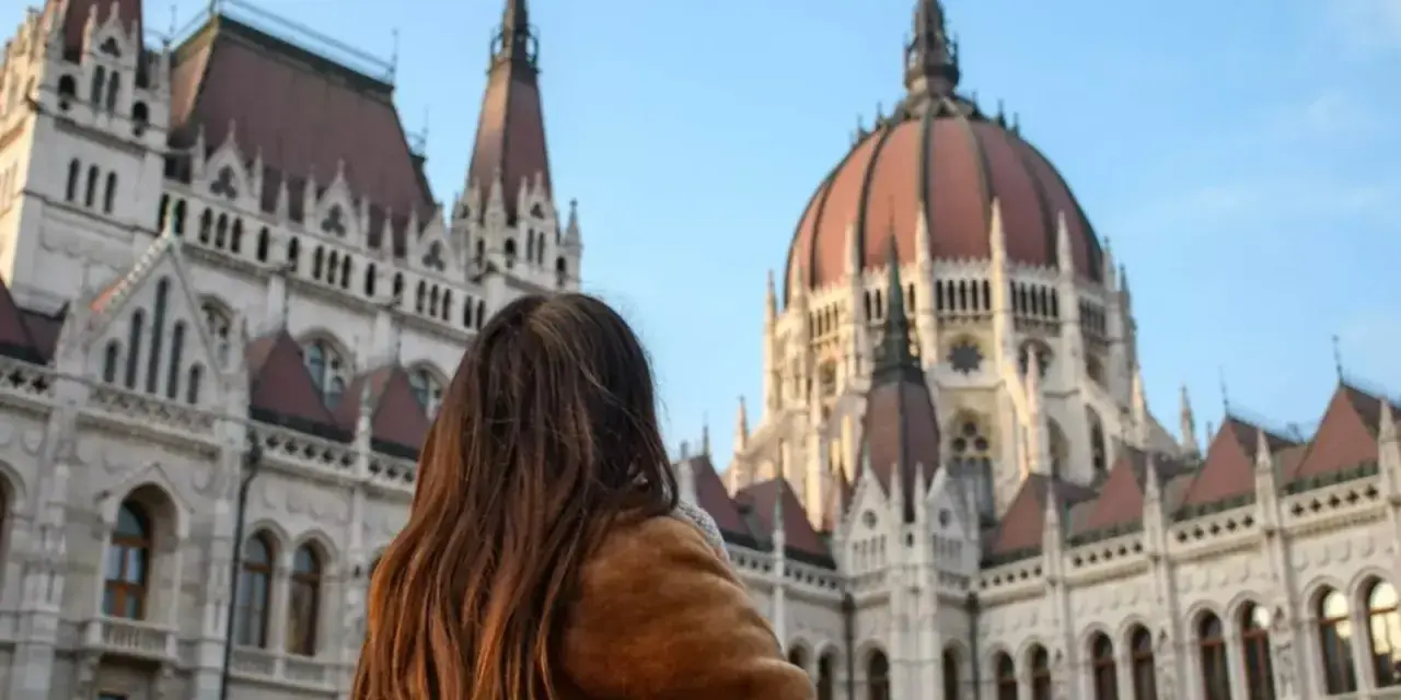 Mujer con abrigo de pelo admira el Parlamento de Budapest, un destino ideal donde viajar en noviembre en Europa.