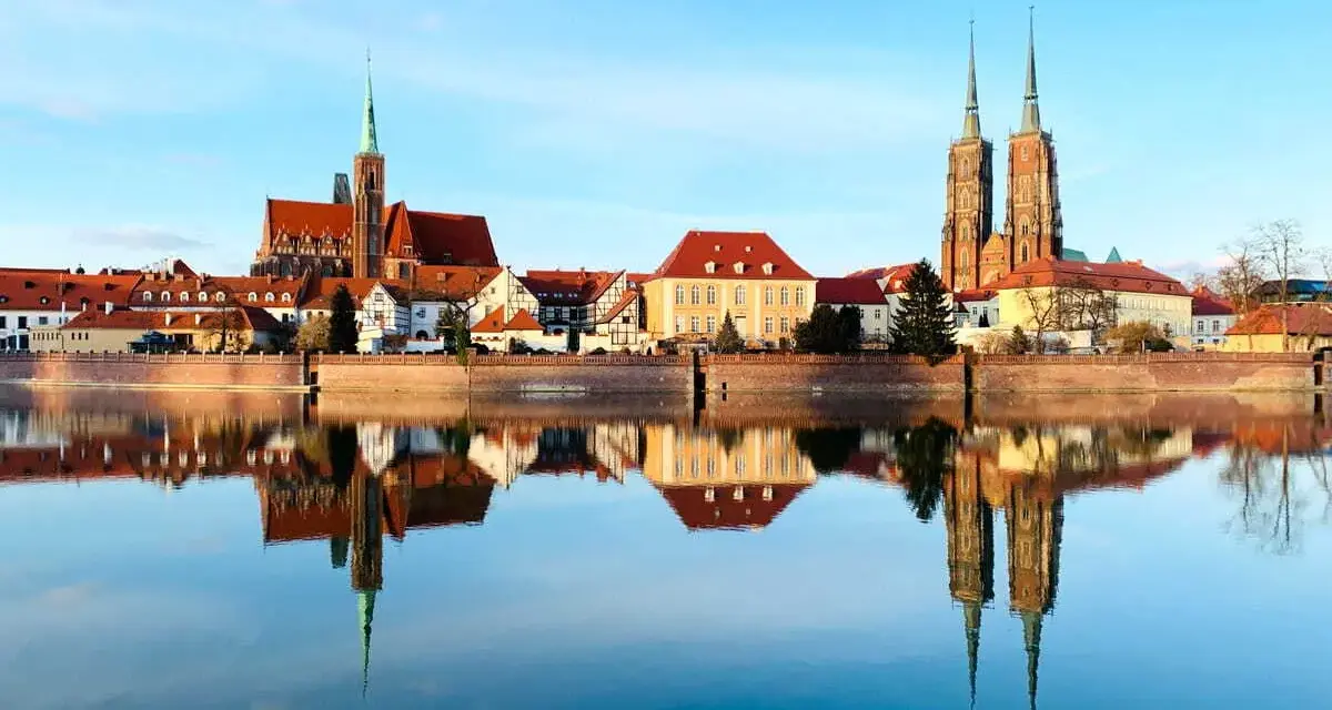 Imponente skyline de Breslavia, Polonia, con sus iglesias y edificios históricos reflejados en el sereno río Odra.