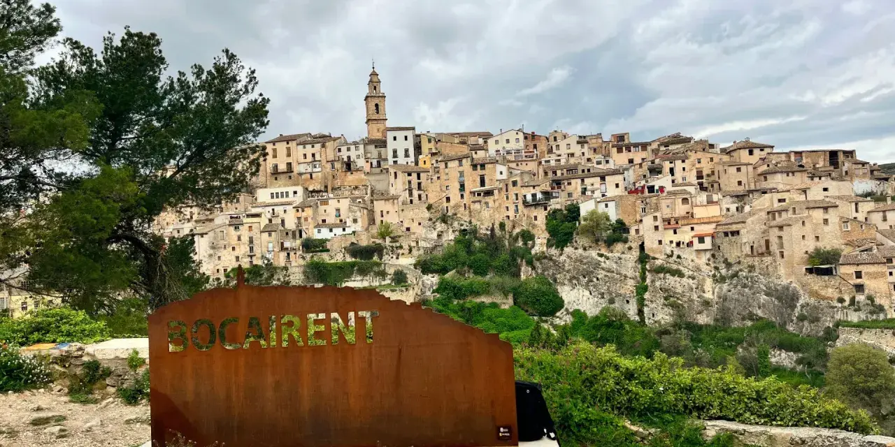 Cartel de "Bocairent" con el pueblo al fondo. Descubre qué ver en Bocairent, un pueblo colgado en la roca.