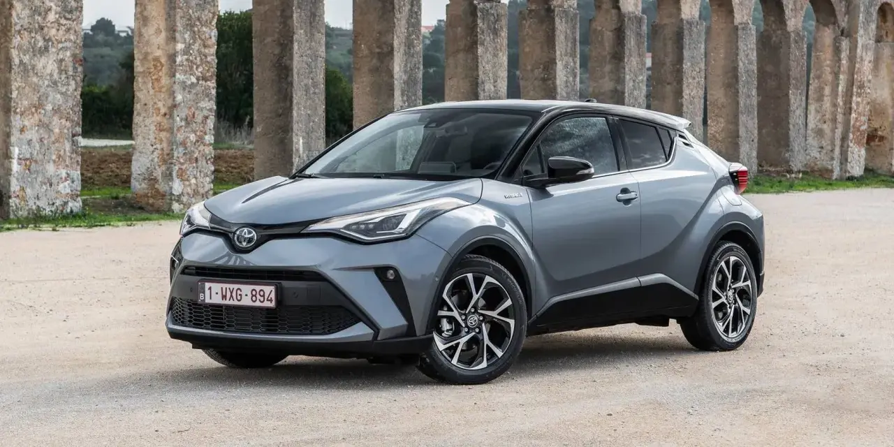 Toyota C-HR gris, un coche ideal para quienes buscan coches baratos de mantener, aparcado frente a un acueducto.