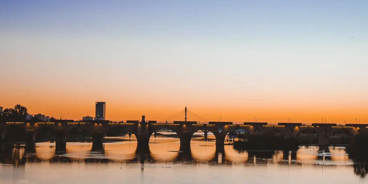 Atardecer sobre el río Guadiana, con el Puente de Palmas iluminado. Un paisaje idílico para descubrir qué ver en Badajoz.