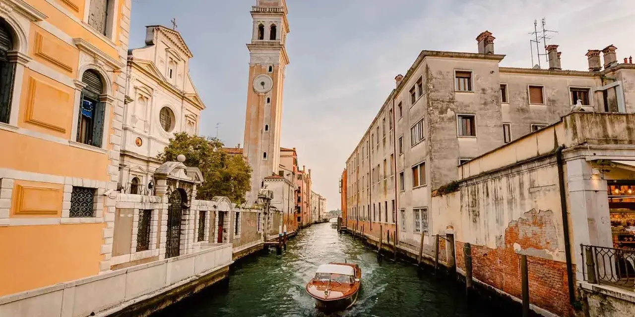 Un canal veneciano con un barco de madera y edificios antiguos. ¿Cuántos días para ver Venecia?