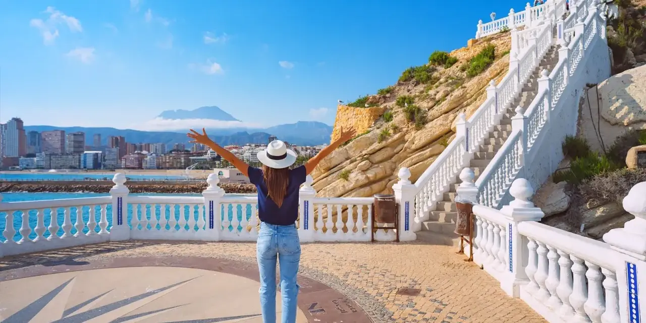 Mujer con brazos abiertos admira la vista de Benidorm desde el mirador. ¡Un lugar ideal que ver en Benidorm!