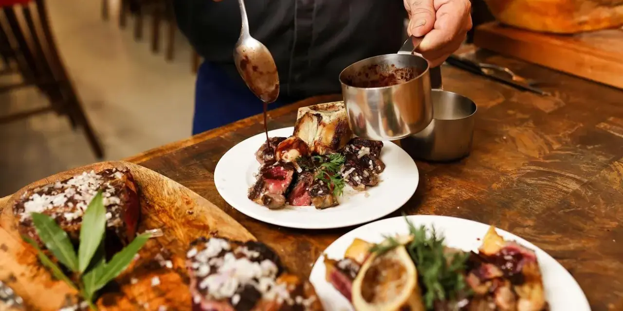 Chef sirve salsa sobre un bistec jugoso, listo para comer en Burdeos.