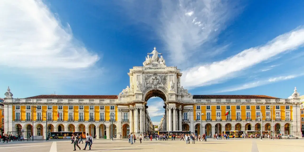 Arco da Rua Augusta y Praça do Comércio, un lugar ideal que ver en Lisboa en 3 días. Gente paseando bajo el cielo azul.