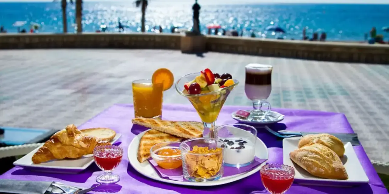 Desayuno frente al mar en Calpe: cruasanes, tostadas, fruta fresca, yogur y café. ¡Un lugar ideal donde comer en Calpe!