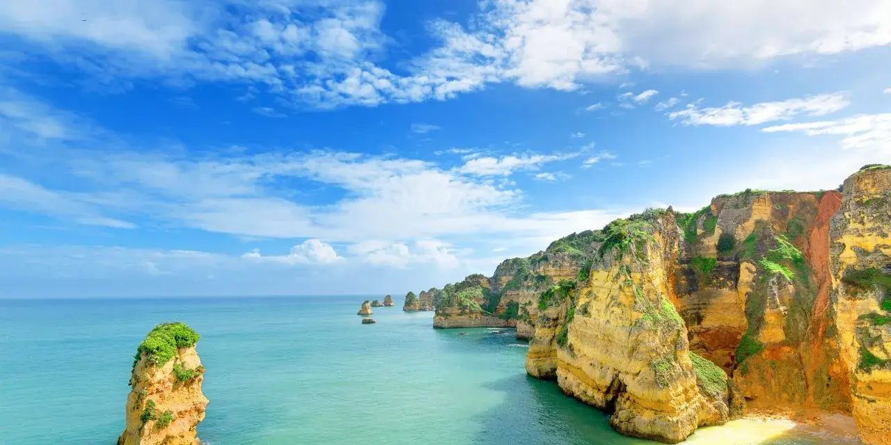 Acantilados dorados y mar turquesa. Un lugar idílico para saber donde viajar en agosto barato y disfrutar de la naturaleza.