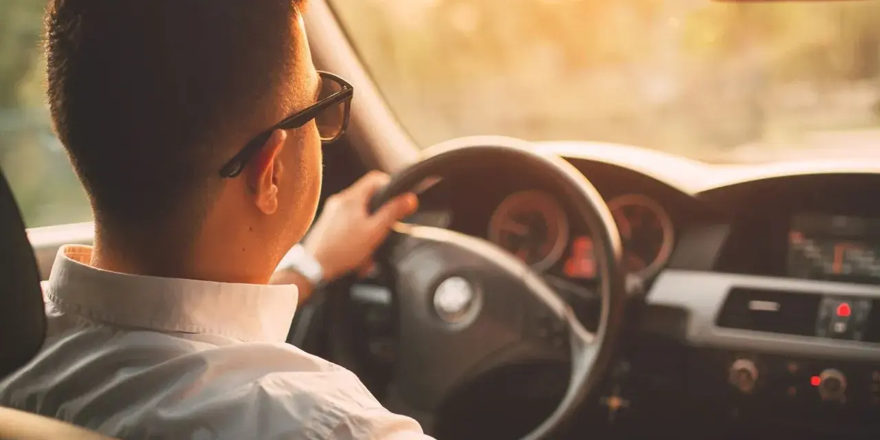Hombre con gafas de sol conduce al atardecer. ¡Cuidado con la velocidad, te pueden multar!