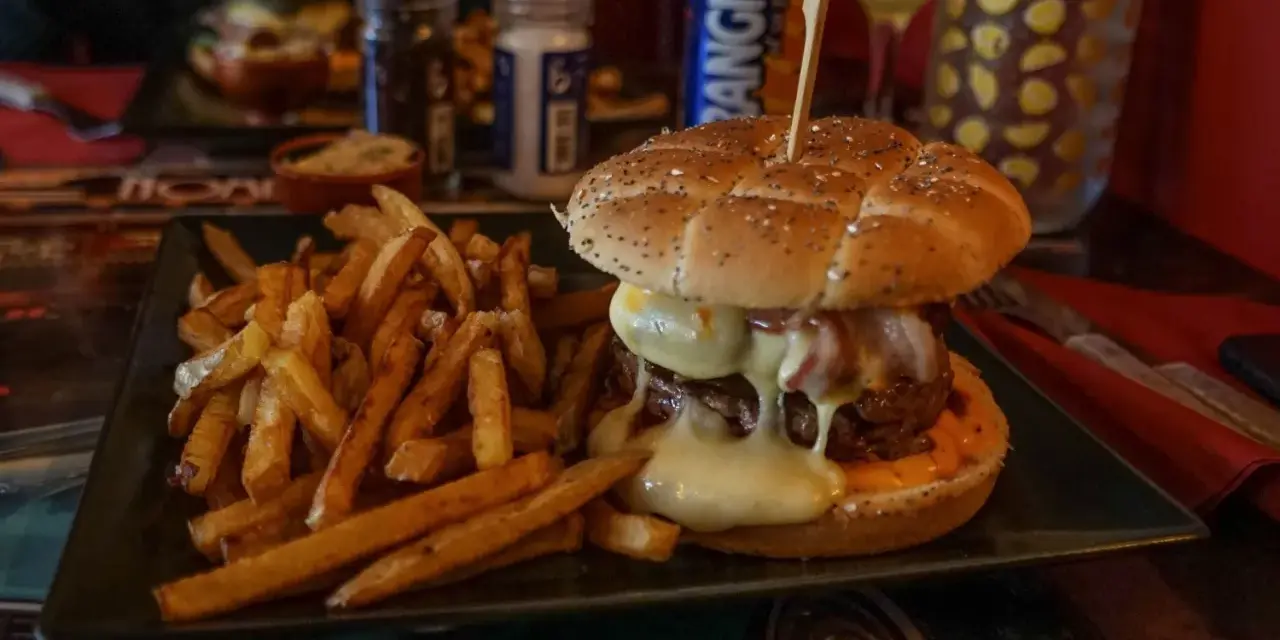 Jugosa hamburguesa con queso fundido y patatas fritas, ideal para saber donde comer en Carcassonne.
