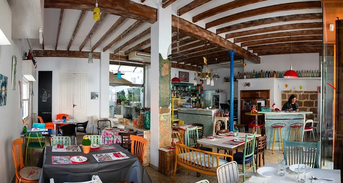 Un restaurante acogedor en Dénia, con mesas coloridas y vigas de madera. Ideal para saber donde comer en Dénia.