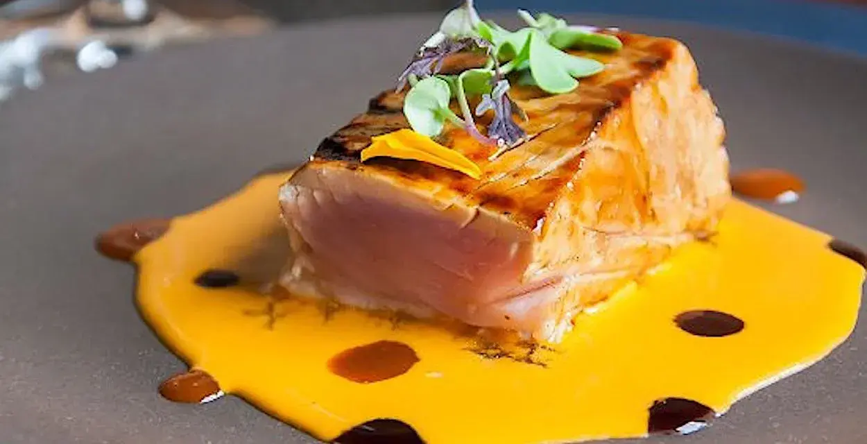 Un delicioso atún sellado sobre una cremosa salsa de naranja, perfecto para comer en Cambados.