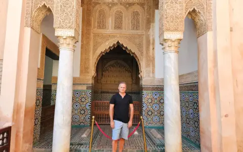 Hombre posa ante intrincada arquitectura marroquí. ¡Ideas para que ver en Marrakech en 2 días!