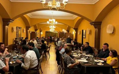 Gente disfrutando de una cena en un elegante restaurante con arcos y lámparas doradas. Una experiencia culinaria memorable para comer en Olite.
