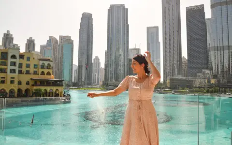 Mujer disfrutando de su viaje a Dubai, con rascacielos y una fuente de agua de fondo.
