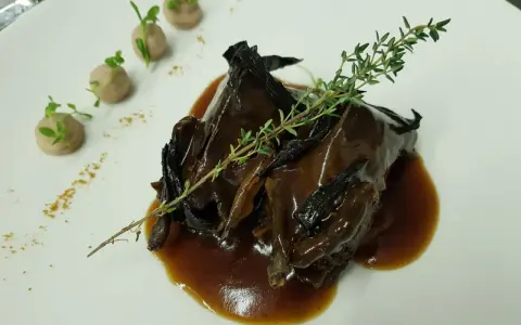Plato de caza en salsa oscura, decorado con tomillo y puré de patatas. ¡Una opción deliciosa donde comer en Úbeda!