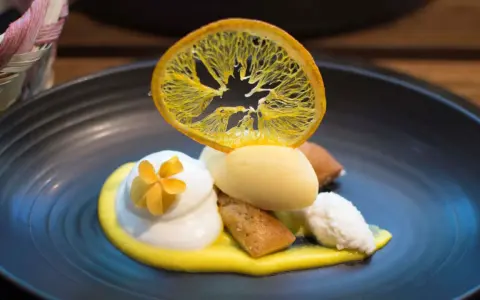 Postre de autor con helado de limón, merengue, bizcocho y naranja deshidratada. ¡Una delicia para saber dónde comer en Barcelona!