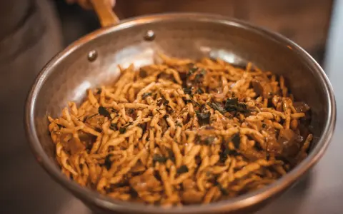 Pasta con salsa cremosa y hierbas en sartén. ¡Una deliciosa opción para saber dónde comer en Madrid!