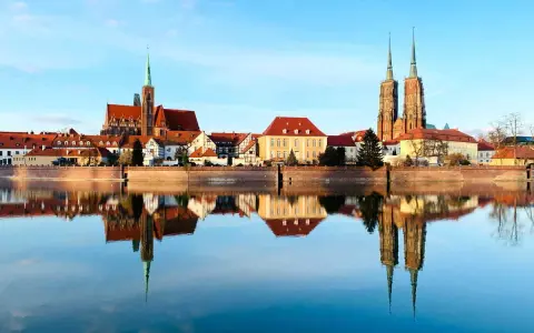 Imponente skyline de Breslavia, Polonia, con sus iglesias y edificios históricos reflejados en el sereno río Odra.