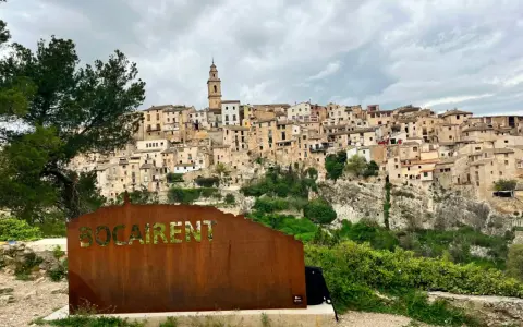Cartel de "Bocairent" con el pueblo al fondo. Descubre qué ver en Bocairent, un pueblo colgado en la roca.