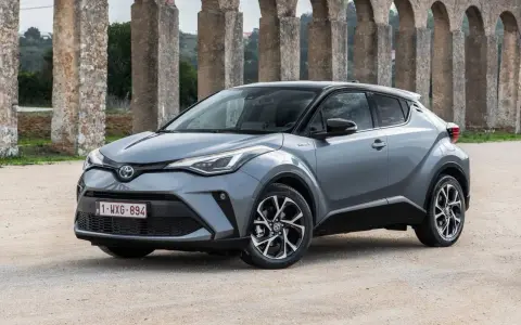 Toyota C-HR gris, un coche ideal para quienes buscan coches baratos de mantener, aparcado frente a un acueducto.