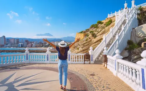 Mujer con brazos abiertos admira la vista de Benidorm desde el mirador. ¡Un lugar ideal que ver en Benidorm!