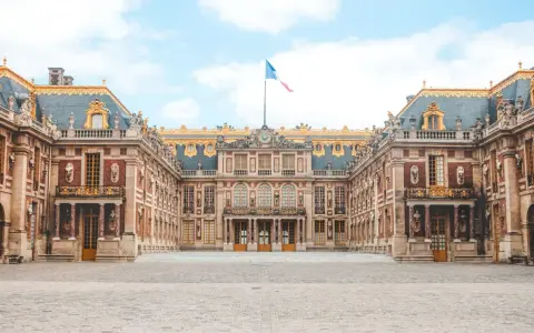 Palacio de Versalles, una visita obligada si buscas qué ver en París en 2 días. Majestuosa arquitectura y bandera francesa ondeando.